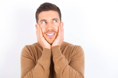 Inspired young caucasian man wearing turtleneck over white background looking at copyspace having thoughts about future events