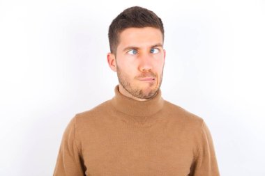 young caucasian man wearing turtleneck over white background making grimace and crazy face, screaming out of control, funny lunatic expressing freedom and wild.