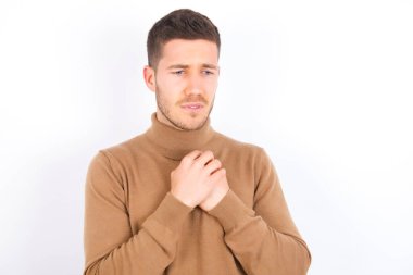Sad young caucasian man wearing turtleneck over white background desperate and depressed with tears on her eyes suffering pain and depression  in sadness facial expression and emotion concept