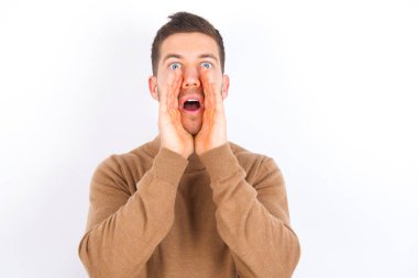 young caucasian man wearing turtleneck over white background shouting excited to front.
