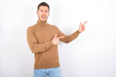 young caucasian man wearing turtleneck over white background point at copyspace recommend sales discounts