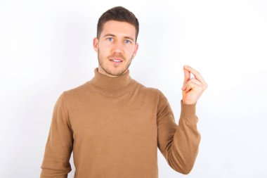 young caucasian man wearing turtleneck over white background pointing up with hand showing up seven fingers gesture in Chinese sign language Q.