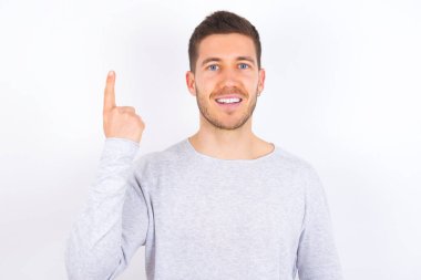 young caucasian man wearing casual clothes over white background smiling and looking friendly, showing number one or first with hand forward, counting down