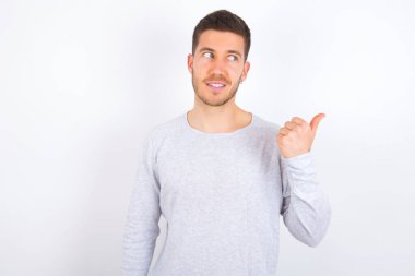 young caucasian man wearing casual clothes over white background points away and gives advice demonstrates advertisement