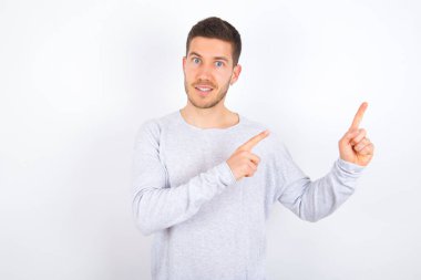 young caucasian man wearing casual clothes over white background points at copy space indicates for advertising gives right direction