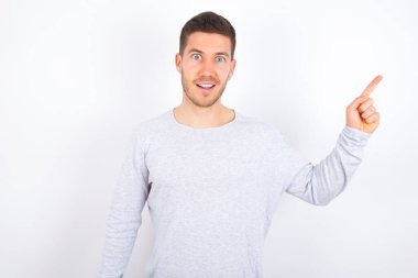 young caucasian man wearing casual clothes over white background points aside on copy blank space. People promotion and advertising concept
