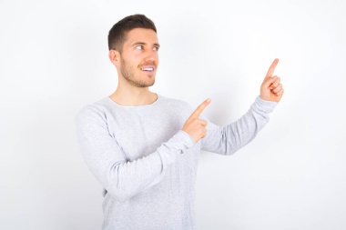 young caucasian man wearing casual clothes over white background smile excited directing fingers look empty space
