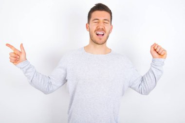 Cheerful young caucasian man wearing casual clothes over white background showing copy space ad celebrating luck