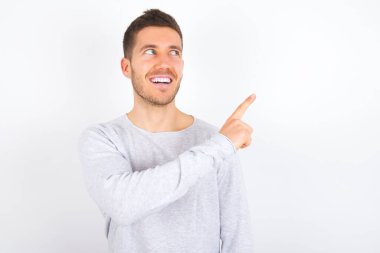 young caucasian man wearing casual clothes over white background glad cheery demonstrating copy space look novelty