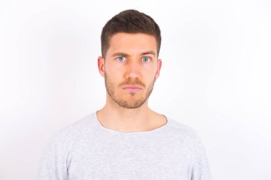 Displeased young caucasian man wearing casual clothes over white background frowns face feels unhappy has some problems. Negative emotions and feelings concept