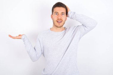 Shocked amazed surprised young caucasian man wearing casual clothes over white background hold hand offering proposition