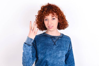young caucasian woman red haired wearing blue T-shirt over white background smiling and looking friendly, showing number four or fourth with hand forward, counting down