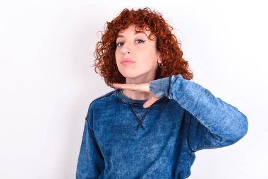 young caucasian woman red haired wearing blue T-shirt over white background cutting throat with hand as knife, threaten aggression with furious violence.