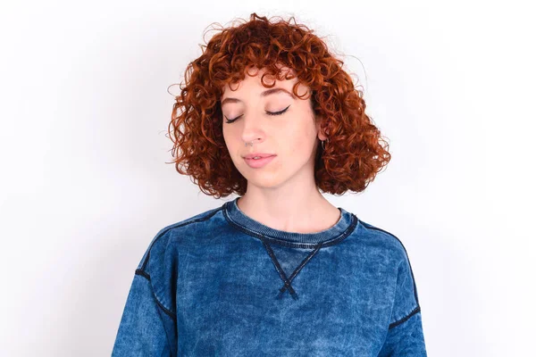 young caucasian woman red haired wearing blue T-shirt over white background nice-looking sweet charming cute attractive lovely winsome sweet peaceful closed eyes