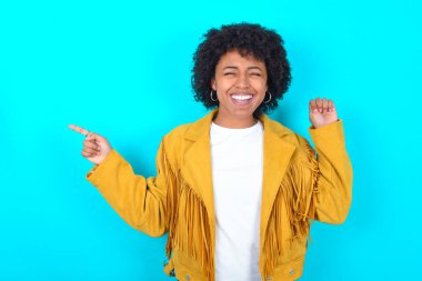 Mavi arka planda sarı püsküllü ceket giyen neşeli Afro-Amerikalı kadın şans kutlayan fotokopi alanı reklamı gösteriyor.
