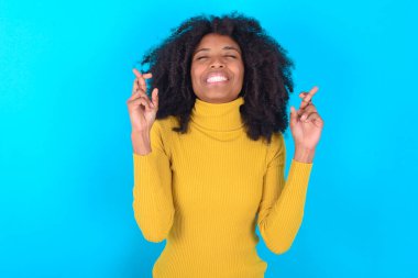 Mavi arka planda sarı boğazlı kazak giyen Afro-Amerikalı kadının büyük umutları var, şans diliyor, bol bol gülüyor. İnsanlar ve dilek kavramı