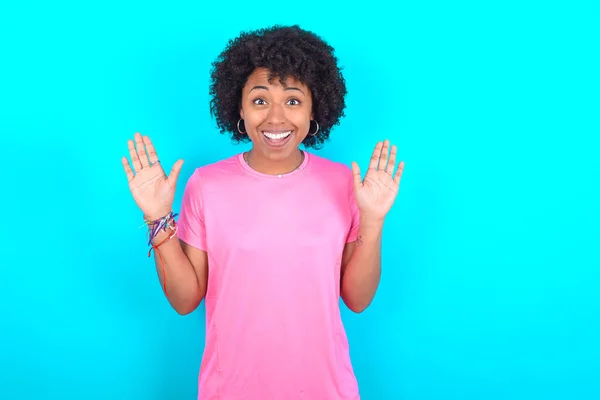 Optymistyczna Młoda Afroamerykanka Ubrana Różowy Shirt Niebieskim Tle Podnosi Dłonie — Zdjęcie stockowe