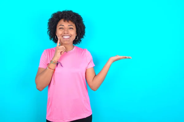 Zabawna Młoda Afroamerykanka Ubrana Różowy Shirt Niebieskim Tle Trzymać Otwartą — Zdjęcie stockowe
