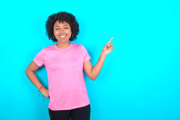 Młoda Afroamerykanka Ubrana Różowy Shirt Niebieskim Tle Patrząc Aparat Wskazujący — Zdjęcie stockowe