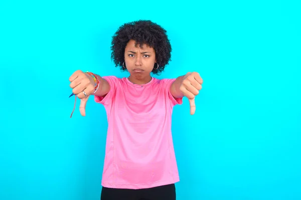 Młoda Afroamerykanka Ubrana Różowy Shirt Niebieskim Tle Zdenerwowana Pokazem Kciuka — Zdjęcie stockowe
