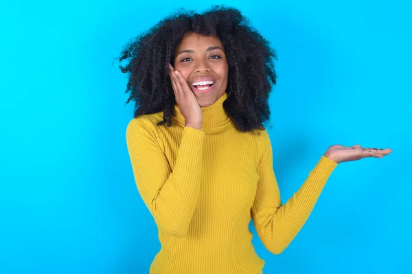 Crazy Afro Amerikaanse Vrouw Draagt Gele Coltrui Blauwe Achtergrond Adviseren — Stockfoto