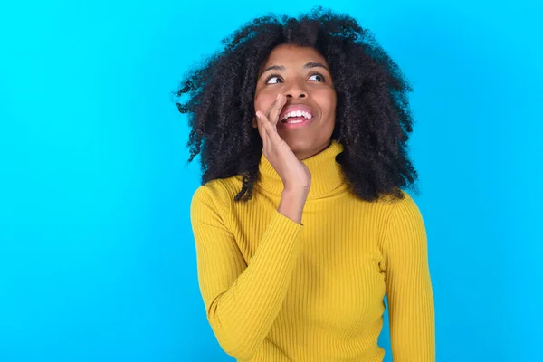 Afro Amerikaanse Vrouw Draagt Gele Coltrui Blauwe Achtergrond Horen Ongelooflijke — Stockfoto