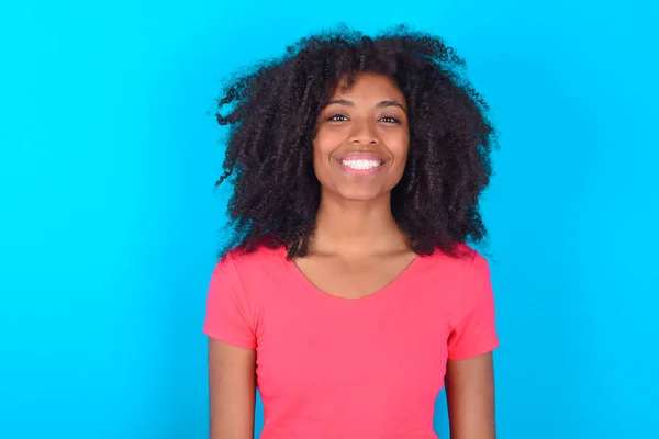 Afroamerykanka Ubrana Różowy Shirt Niebieskim Tle Ładnym Uśmiechem Uśmiechem Zadowolonym — Zdjęcie stockowe
