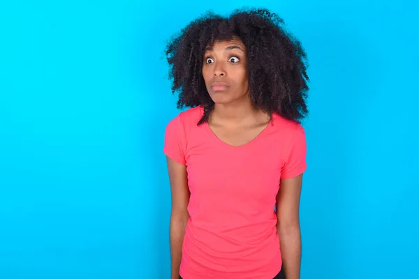 Afroamerykanka Ubrana Różowy Shirt Niebieskim Tle Spogląda Siebie Dziwnym Wyrazem — Zdjęcie stockowe