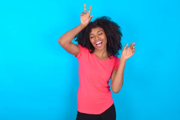 Zdjęcie Optymistycznej Afroamerykanki Ubranej Różowy Shirt Niebieskim Tle Bawi Tańczy — Zdjęcie stockowe