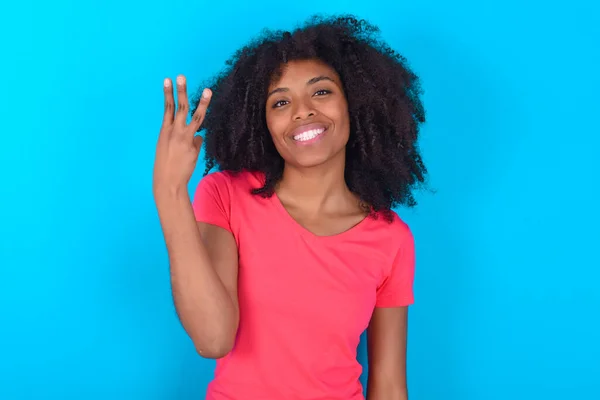 파란색 배경에 티셔츠를 아프리카 미국인 여성이 웃으며 보이며 앞으로 모습을 — 스톡 사진