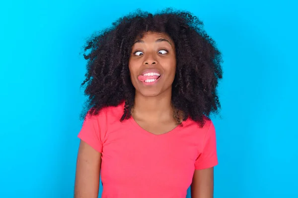 Zabawna Afroamerykanka Ubrana Różowy Shirt Niebieskim Tle Sprawia Grymas Krzyże — Zdjęcie stockowe