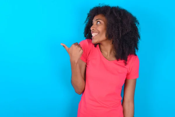 Afroamerikansk Kvinna Bär Rosa Shirt Över Blå Bakgrund Pekar Bort — Stockfoto