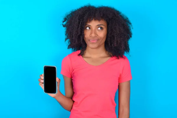 Mujer Afroamericana Vistiendo Camiseta Rosa Sobre Fondo Azul Sostiene Nuevo — Foto de Stock