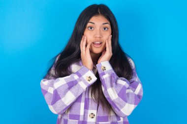 Mavi arka plan üzerine ekose gömlek giyen korkmuş genç Latin kadın dükkandaki, insani ve insani duygular kavramındaki fiyatlarla şok oldu.