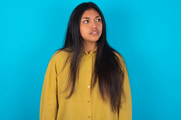 Young Latin Woman Wearing Yellow Shirt Blue Background Stares Aside — Stock fotografie