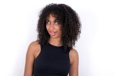 Young African American woman wearing black T-shirt over white background showing grimace face crossing eyes and showing tongue. Being funny and crazy