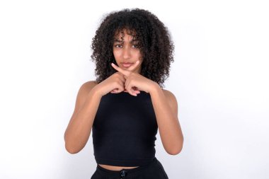 Young African American woman wearing black T-shirt over white background Has rejection angry expression crossing fingers doing negative sign.
