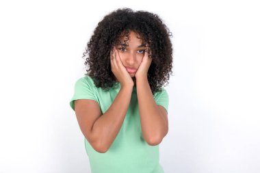 Young African American woman wearing green T-shirt over white background Tired hands covering face, depression and sadness, upset and irritated for problem
