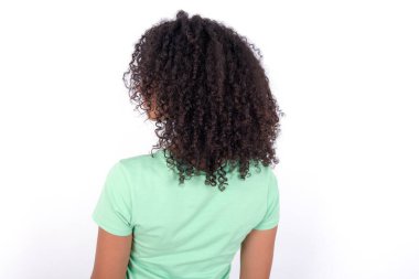 The back side view of a Young African American woman wearing green T-shirt over white background . Studio Shoot.
