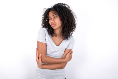 Young African American woman wearing grey T-shirt over white background shaking and freezing for winter cold with sad and shock expression on face.