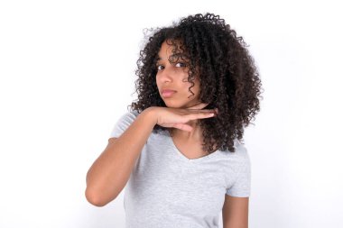 Young African American woman wearing grey T-shirt over white background cutting throat with hand as knife, threaten aggression with furious violence.