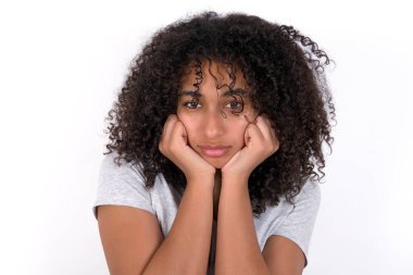 Portrait of sad Young African American woman wearing grey T-shirt over white background hands face