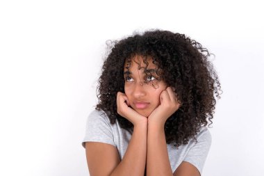 Portrait of sad Young African American woman wearing grey T-shirt over white background hands face look empty space