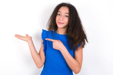 Afro saçlı genç kız beyaz arka planda mavi tişört giyiyor ve el ele tutuşup reklamları gösteriyor.