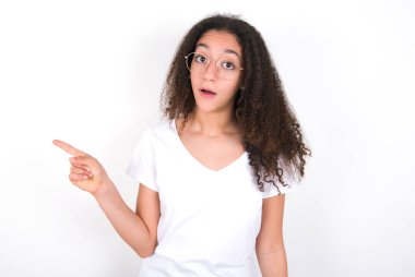 Beyaz arka planda beyaz tişörtlü, afro saçlı duygusal ergen bir kız şoktan çenesini düşük tutuyor. Boş alandaki inanılmaz reklam noktaları büyük bir alışveriş satışını gösteriyor. Reklam.