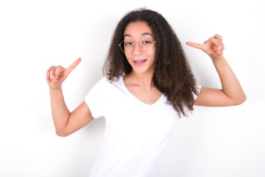 Afro saç stili, beyaz arka planda beyaz tişört giyen neşeli genç kız saç modelini gösteriyor.