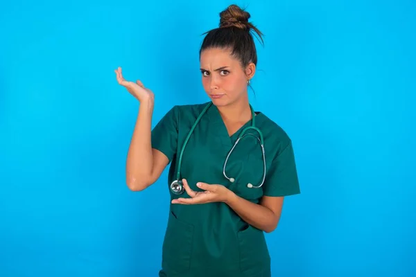 Hermosa Doctora Hispana Vistiendo Uniforme Médico Verde Sobre Fondo Azul —  Fotos de Stock