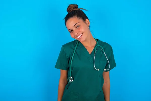 青い背景に緑の制服を着た美しいヒスパニック系の医師の女性は非常に幸せと新しい計画に興奮 — ストック写真