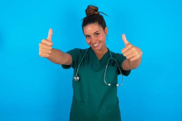 Hermosa Doctora Hispana Vistiendo Uniforme Médico Verde Sobre Fondo Azul —  Fotos de Stock