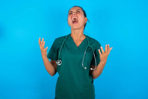 Hermosa Doctora Hispana Vistiendo Uniforme Médico Verde Sobre Fondo Azul — Foto de Stock